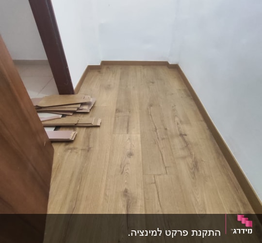 רצפת פרקט מותקנת בחדר עם לוחות עץ בצד